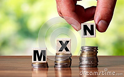 MXN Mexico currency word symbol - business concept. Hands put wooden block on stacked increasing coin Stock Photo