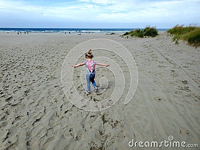 My baby running into the wind with their arms out running towards the ocean Editorial Stock Photo