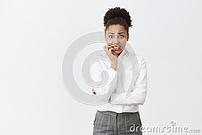 My boss gonna kill me. Nervous attractive african female employee in shirt and pants, biting fingernails from anxiety Stock Photo