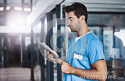 My device helps me be more efficient. a young handsome male medical practitioner working in a hospital. Stock Photo