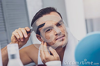 Pleasant cheerful man holding a comb Stock Photo