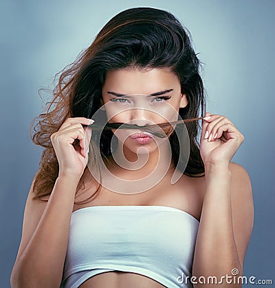 My hair smells amazing. Studio shot of a young woman smelling her hair against a blue background. Stock Photo