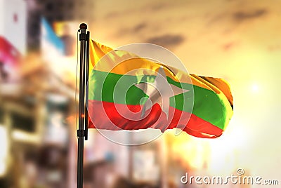 Myanmar Flag Against City Blurred Background At Sunrise Backlight Stock Photo