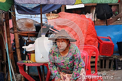 Myanmese woman with thanakha Myanmar powder on her face and wearing conical hat going to sit in a chair Editorial Stock Photo