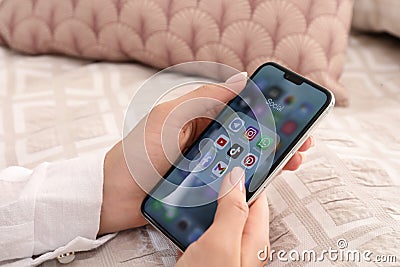MYKOLAIV, UKRAINE - AUGUST 11, 2021: Woman using Apple iPhone X at bed, closeup. Screen with different social media icons Editorial Stock Photo
