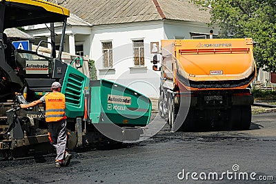 MYKOLAIV, UKRAINE - AUGUST 04, 2021: Worker with road repair machinery laying asphalt Editorial Stock Photo