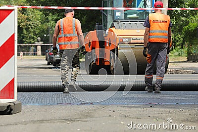 MYKOLAIV, UKRAINE - AUGUST 04, 2021: Workers with road repair machinery laying new asphalt Editorial Stock Photo