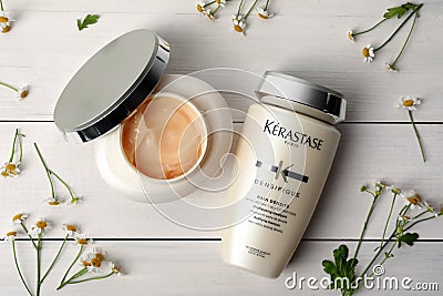 MYKOLAIV, UKRAINE - SEPTEMBER 07, 2021: Kerastase hair care cosmetic products and chamomile flowers on white wooden table, flat Editorial Stock Photo