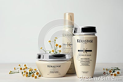 MYKOLAIV, UKRAINE - SEPTEMBER 07, 2021: Set of Kerastase hair care cosmetic products and chamomile flowers on white wooden table Editorial Stock Photo