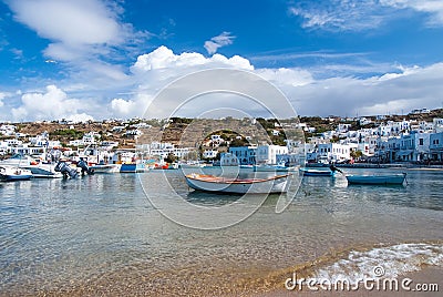 Mykonos, Greece - May 04, 2010: boats on sea water. Sea beach on cloudy blue sky. Houses on mountain landscape with Editorial Stock Photo