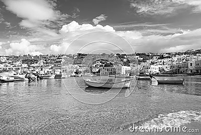 Mykonos, Greece - May 04, 2010: boats on sea water. Sea beach on cloudy blue sky. Houses on mountain landscape with Editorial Stock Photo