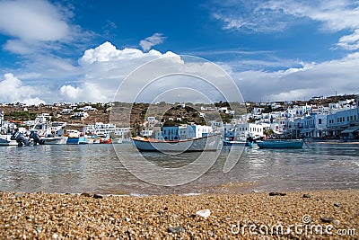 Fishing boats on sea beach in Mykonos, Greece. Sea village on cloudy sky. White houses on mountain landscape with nice Editorial Stock Photo