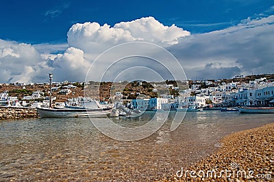 Mykonos, Greece - May 04, 2010: sea beach with boats on cloudy blue sky. Houses on mountain landscape by sea Editorial Stock Photo