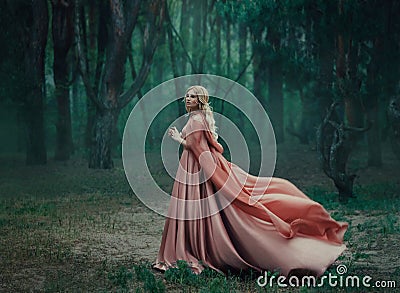 A mysterious blonde girl in a long pink dress with a train and a raincoat that flutters in the wind. The wizard leaves Stock Photo