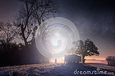 A mysterious concept edit of a lone man silhouetted against a bright light on a winters night in the English countryside Stock Photo