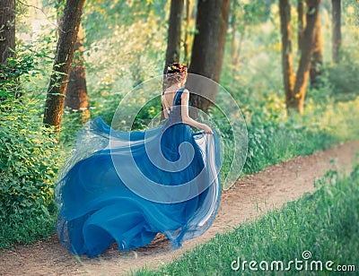 Mysterious girl with red braided hair runs off from royal holiday, lady in long elegant blue dress with flying light Stock Photo