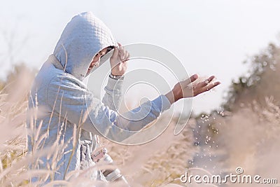 mysterious handsome man in white hoodie standing in the grass field. Stock Photo
