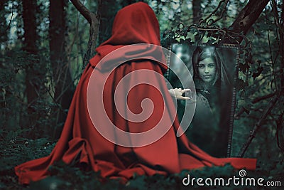 Mysterious hooded woman in front of a magical mirror Stock Photo