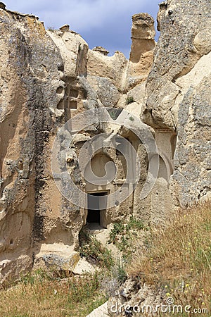 The inconspicuous entrance to the old ancient cave temple in the mountain valley of Cappadocia Stock Photo