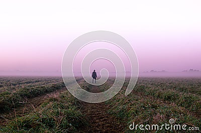 A mysterious lone figure standing in a field on a beautiful early misty morning Stock Photo