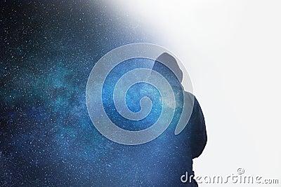 A mysterious moody hooded figure, silhouetted the stars and universe with a double expsoure. with white copy space Stock Photo
