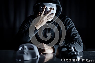 Mystery man looking at mask on the table Stock Photo