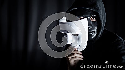 Mystery man in black mask holding white mask Stock Photo