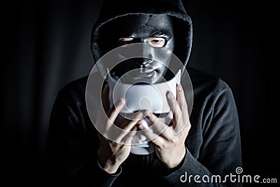 Mystery man in black mask holding white mask Stock Photo