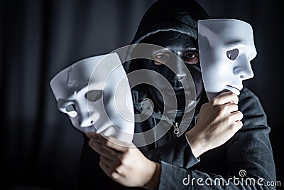 Mystery man in black mask holding white masks Stock Photo