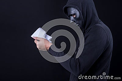 Mystery man holding and looking at white mask Stock Photo