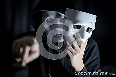 Mystery man pointing and holding white mask Stock Photo