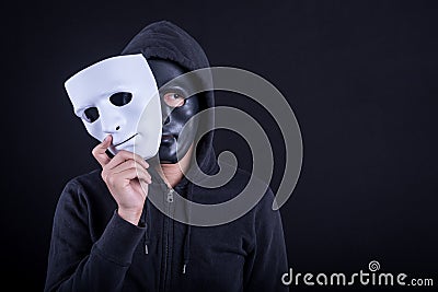 Mystery man wearing black mask holding white mask Stock Photo