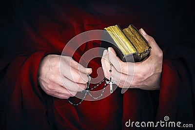 Mystery monk with a cape holding bibles and a black rosary Stock Photo