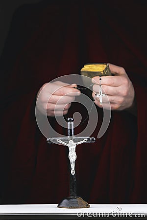 Mystery monk's hands with a cape, bible, a black rosary and cr Stock Photo