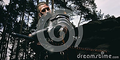 Mystery scarface knight in armor with sword and crossbow in the forest Stock Photo