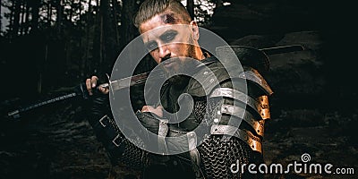 Mystery scarface knight in armor with sword and crossbow in the forest Stock Photo