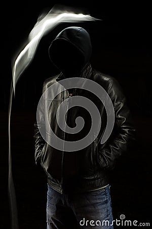 Mystic black hooded man standing in the darkness. Stock Photo