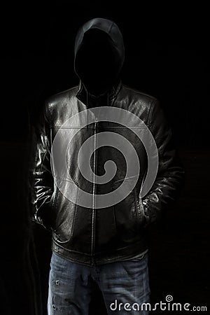 Mystic black hooded man standing in the darkness. Stock Photo