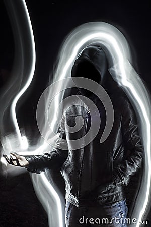 Mystic black hooded man standing in the darkness. Stock Photo