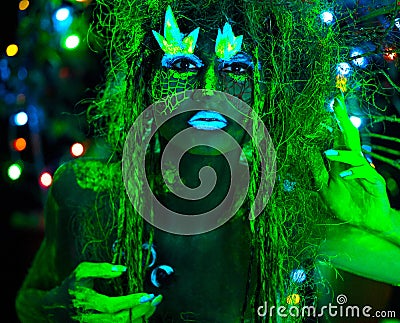 Mystic green dryad in UV fluor black light with Glowing trees on background Stock Photo