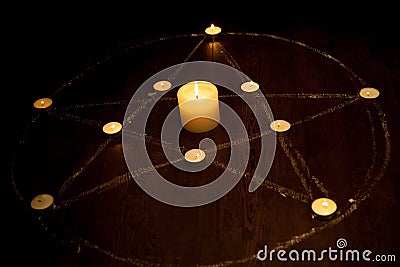 Mystic pentagram with fired candles in darkness, on wooden background Stock Photo