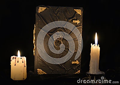 Mystic still life with black magic book and two burning candles Stock Photo