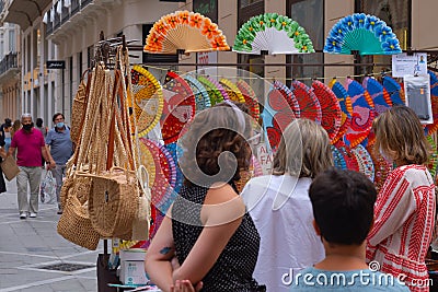 MÃ¡laga, Spain - June 19, 2021: People shopping hand fans on streets of Malaga Spain Editorial Stock Photo