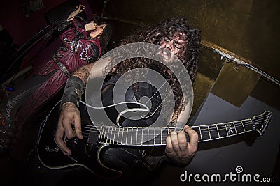 Bearded long-haired man playing guitar next to a female rocker vocalist Editorial Stock Photo