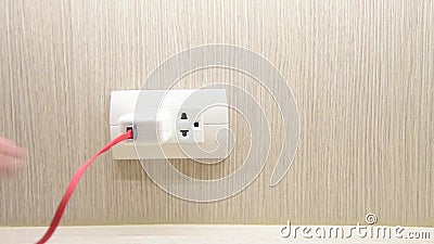 A mão retira o adaptador do carregador que desconecta o em uma tomada elétrica típica filme A mão retira o adaptador do carregador que desconecta o em uma tomada elétrica típica filme