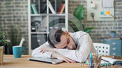 Müder Geschäftsmann, der an Arbeitsplatz am Schreibtisch mit Kopf auf Laptop-Computer schläft Müder Geschäftsmann, der an Arbeitsplatz am Schreibtisch mit Kopf auf Laptop-Computer schläft