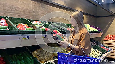 Młoda kobieta z koszykiem na zakupy wybierająca świeże warzywa w sklepie spożywczym zbiory wideo Młoda kobieta z koszykiem na zakupy wybierająca świeże warzywa w sklepie spożywczym zbiory wideo