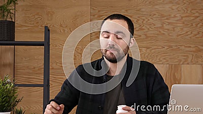 Młody biznesmen bierze medycynę podczas gdy siedzący przy miejsce pracy przed laptopem zdjęcie wideo Młody biznesmen bierze medycynę podczas gdy siedzący przy miejsce pracy przed laptopem zdjęcie wideo