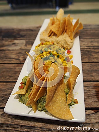 Nachos with Guacamole and Salsa on Wooden Table Stock Photo