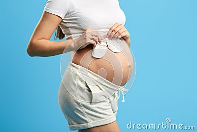 Nacked belly of a pregnant woman with two pairs of baby mittens Stock Photo